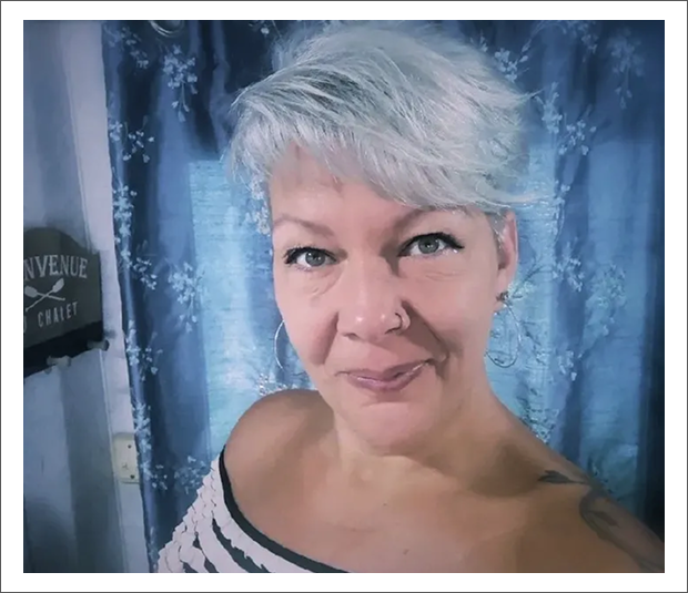 Woman with short hair, floral curtain background.