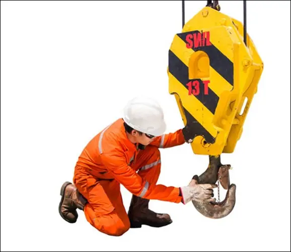 Worker in orange safety gear inspecting a crane hook.